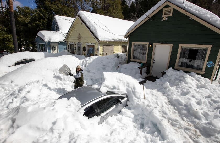 CRESTLINE, CA - MARCH 07: Kadyn Wheat, 14, shovels snow as he works to free the family car, entombed after successive snow storms paralyzed the region in the San Bernardino Mountain community on Tuesday, March 7, 2023 in the Valley of Enchantment, CA. (Brian van der Brug / Los Angeles Times)