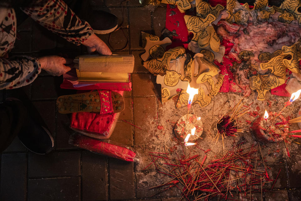 A practitioner performs a "villain hitting" ceremony near papers with images of tigers on the day of "ging zat," as pronounced in Cantonese, which on the Chinese lunar calendar literally means "awakening of insects," under the Canal Road Flyover in Hong Kong on Monday, March 6, 2023. People holding a grudge may have found a way to release it in Hong Kong’s “villain hitting” ritual. To relieve themselves from a bad mood, customers paid ritual practitioners who work underneath the Canal Road Flyover in Causeway Bay, one of the city's shopping districts, and watched them bashing an image of their target with a shoe. It could be anyone — rival lovers and unfriendly colleagues, or horrible bosses and unlikeable public figures. (AP Photo/Louise Delmotte)