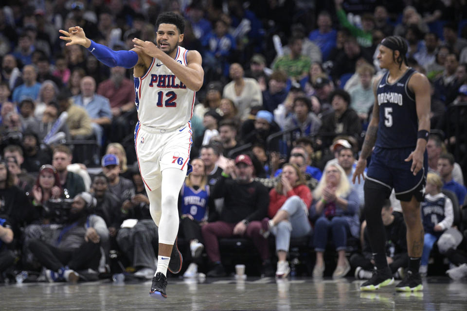 Philadelphia 76ers forward Tobias Harris (12) celebrates his 3-pointer as Orlando Magic forward Paolo Banchero (5) reacts during the second half of an NBA basketball game, Wednesday, Dec. 27, 2023, in Orlando, Fla. (AP Photo/Phelan M. Ebenhack)