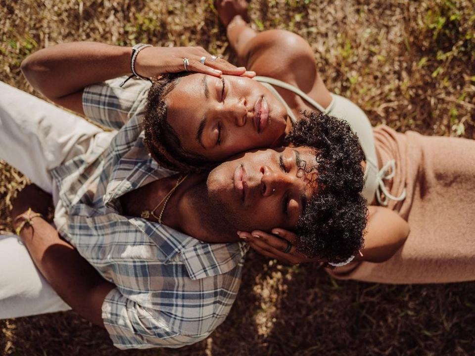 Two people, eyes closed, with their heads together, back-to-back, and faces turned up to the camera