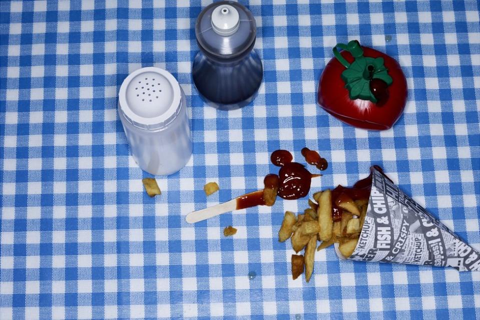 Mesa con sal, salsa de tomate, vinagre y papas fritas