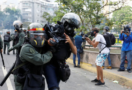 A cameraman is helped by riot police during a rally against Venezuela's President Nicolas Maduro in Caracas, Venezuela, April 26, 2017. REUTERS/Carlos Garcia Rawlins