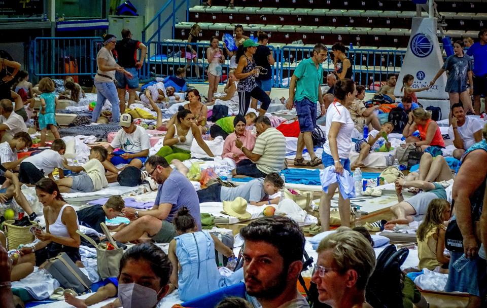 Evacuees sit inside a stadium after fleeing a forest fire on the island of Rhodes, Greece, on July 23, 2023.