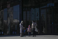 Women with their children walk through a deserted walkway outside a closed shopping mall in Beijing, Sunday, Dec. 4, 2022. China on Sunday reported two additional deaths from COVID-19 as some cities move cautiously to ease anti-pandemic restrictions amid increasingly vocal public frustration over the measures. (AP Photo/Andy Wong)