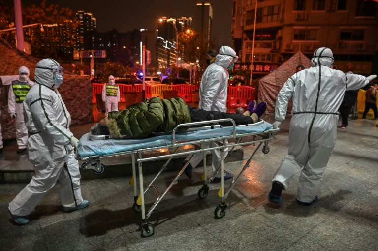 Personal m&#xe9;dico con indumentaria protectora llega con un paciente en camilla al hospital de la Cruz Roja de Wuhan, el 25 de enero de 2020 en la ciudad china, al inicio de la epidemia del coronavirus