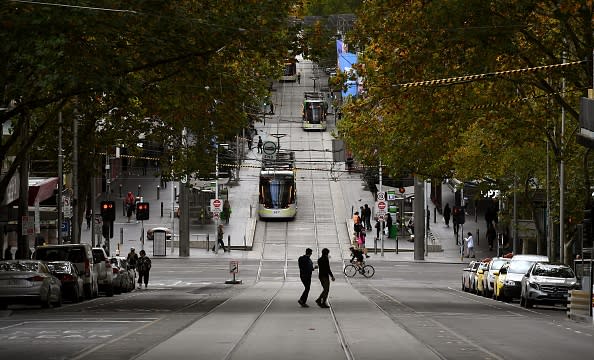 Pedestrians cross a deserted street in Melbourne's central business district as Australia starts to ease its COVID-19 coronavirus restrictions. 