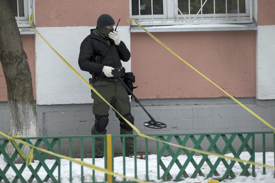 A police officer uses a metal detector outside a Moscow school on Monday, Feb. 3, 2014. An armed teenager burst into his Moscow school on Monday and killed a teacher and policeman before being taken into custody, investigators said. None of the children who were in School No. 263 were hurt, said Karina Sabitova, a police spokeswoman at the scene. The student also wounded a second police officer who had responded to an alarm from the school, she said. (AP Photo/Alexander Zemlianichenko)