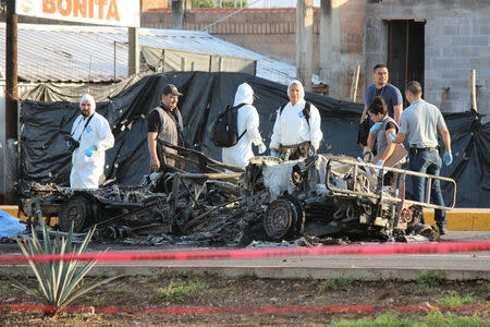 Forensic technicians stand at a crime scene next to the burnt wreckage of a military vehicle, after what local media said was an ambush by gunman on a military convoy to free an injured fellow gunman from an ambulance, in Culiacan, in Sinaloa state, Mexico, September 30, 2016. REUTERS/Jesus Bustamante