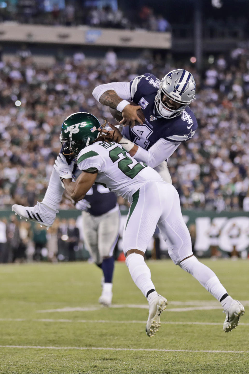 Dallas Cowboys quarterback Dak Prescott, top, tries to leap New York Jets' Darryl Roberts during the second half of an NFL football game, Sunday, Oct. 13, 2019, in East Rutherford, N.J. (AP Photo/Adam Hunger)