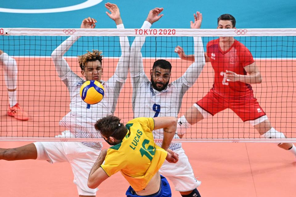 <p>France's Barthelemy Chinenyeze (L) and Earvin Ngapeth (R) block a shot by Brazil's Lucas Saatkamp (C) in the men's preliminary round pool B volleyball match between Brazil and France during the Tokyo 2020 Olympic Games at Ariake Arena in Tokyo on August 1, 2021. (Photo by Anne-Christine POUJOULAT / AFP)</p> 