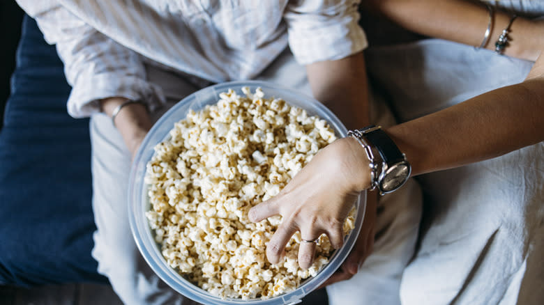 Person reaching into a bowl of popcorn