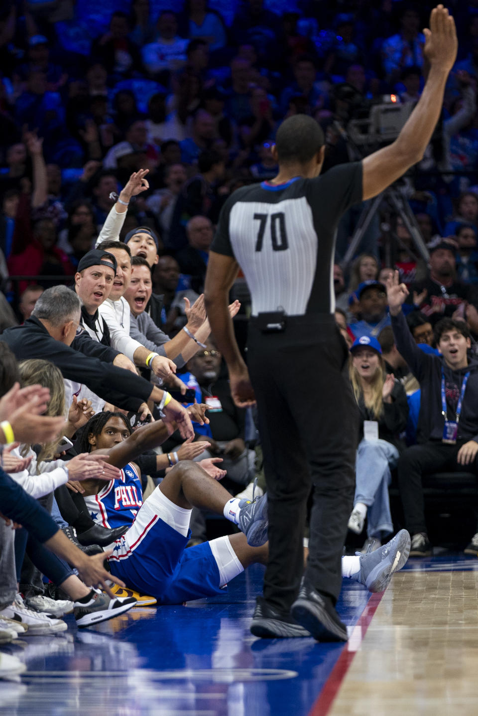 Philadelphia 76ers' Tyrese Maxey, left, falls into the fans after hitting the three point shot during the first half of an NBA basketball game against the Portland Trail Blazers, Sunday, Oct. 29, 2023, in Philadelphia. (AP Photo/Chris Szagola)