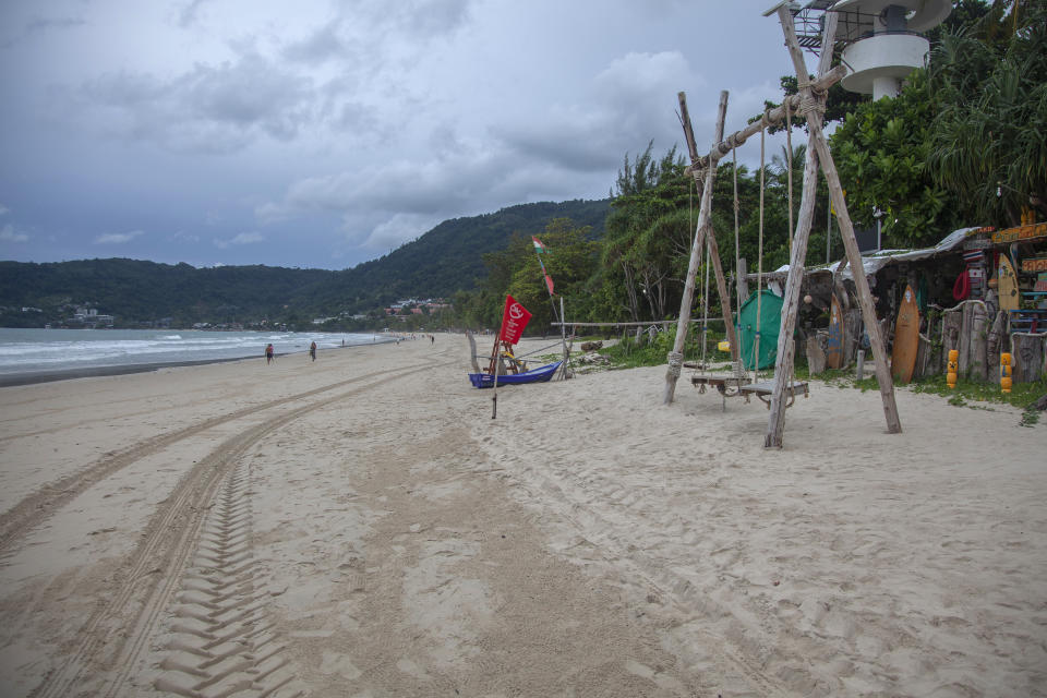 In this Wednesday, July 7, 2021, photo, tourists walk along a mostly empty Patong Beach on Phuket, southern Thailand. A week into an ambitious but risky plan to open the resort island of Phuket to fully-vaccinated visitors, signs were encouraging that the gambit to help breathe new life into the struggling tourism industry was working, even as coronavirus numbers in the rest of Thailand surged Thursday to new record highs. (AP Photo/Tiwa Suvarnabhanu)