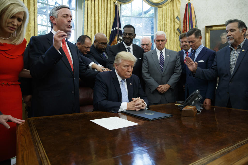 FILE - In this Sept. 1, 2017 file photo, religious leaders pray with President Donald Trump after he signed a proclamation for a national day of prayer to occur on Sunday, Sept. 3, 2017, in the Oval Office of the White House in Washington. As the threat of impeachment looms, President Donald Trump is digging in and taking solace in the base that helped him get elected: conservative evangelical Christians who laud his commitment to enacting their agenda. (AP Photo/Evan Vucci, File
