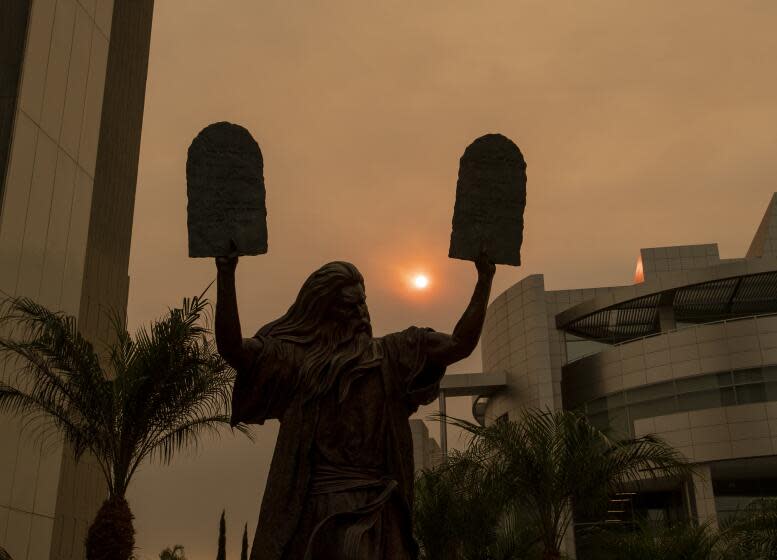 GARDEN GROVE, CA - SEPTEMBER 09: The sun and a bronze statue of Moses putting the ten commandments of two tables in the air are partially obscured with ash from Southland wildfires at the Christ Cathedral in Garden Grove Wednesday, Sept. 9, 2020. With so many fires burning, millions of people in the Bay Area, Central Valley and parts of Southern California are breathing dangerous levels of particle pollution. (Allen J. Schaben / Los Angeles Times)