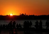 People enjoy a summer day as the sun sets over Hagia Sophia or Ayasofya-i Kebir Camii in Istanbul