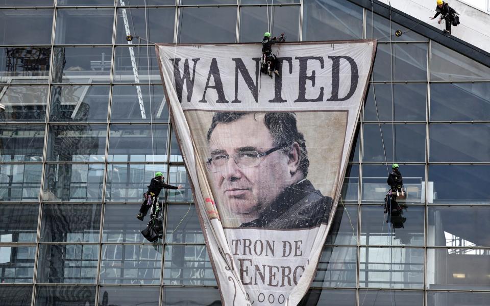 Activists display a banner bearing the portrait of TotalEnergies boss Patrick Pouyanne on a building in Paris