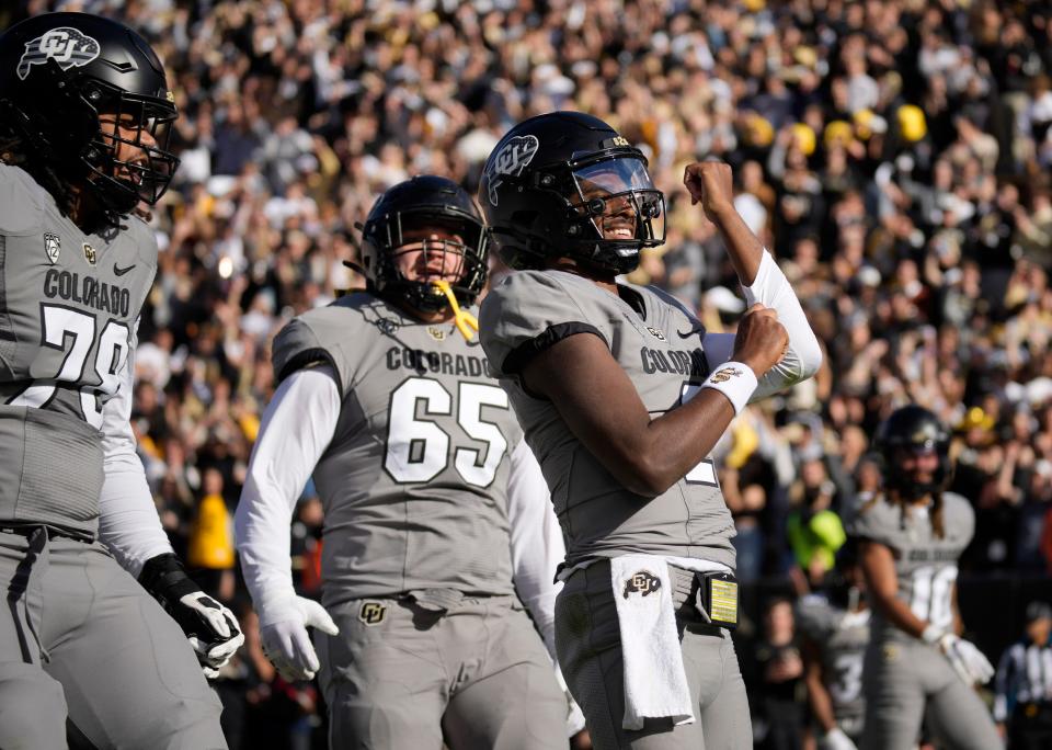 Colorado quarterback Shedeur Sanders, right, gestures to the crowd after scoring a touchdown in the first half of an NCAA college football game against Arizona on Saturday, Nov. 11, 2023, in Boulder, Colo. (AP Photo/David Zalubowski)