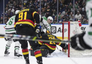 Dallas Stars' Roope Hintz, back center, scores against Vancouver Canucks goalie Casey DeSmith during the first period of an NHL hockey game Thursday, March 28, 2024, in Vancouver, British Columbia. (Darryl Dyck/The Canadian Press via AP)