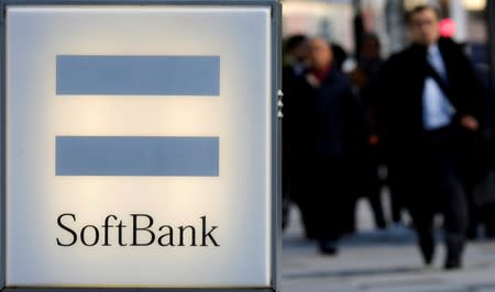 People walk near the logo of SoftBank Corp in Tokyo