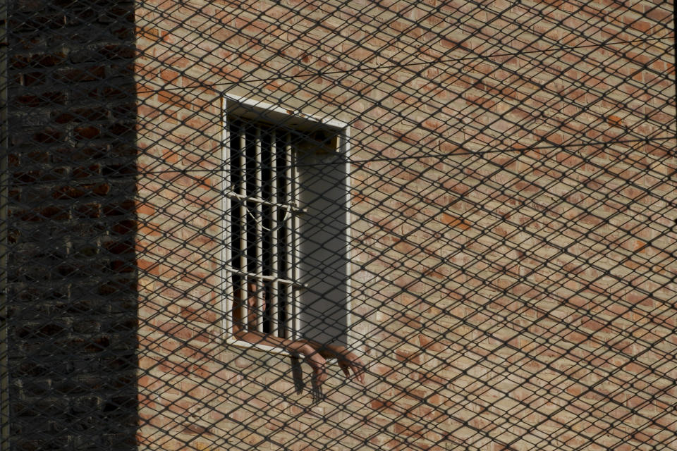 An inmate looks out from a window at Pinero jail in Pinero, Argentina, Tuesday, April 9, 2024. Authorities have ramped up prison raids, seized thousands of smuggled cellphones and restricted visits. (AP Photo/Natacha Pisarenko)