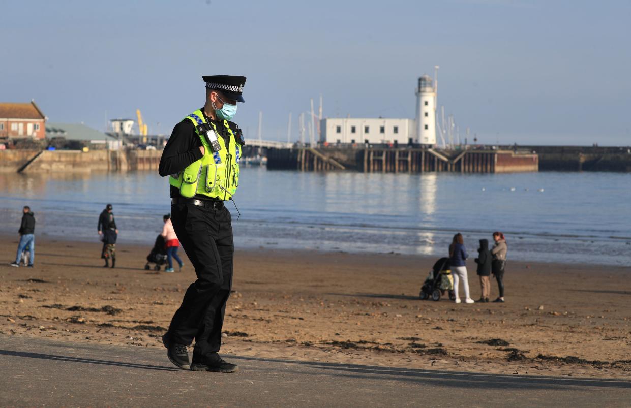 <p>A police officer patrols a  Scarborough beach to turn away sunbathers ignoring the Governments Stay At Home message</p> (PA)