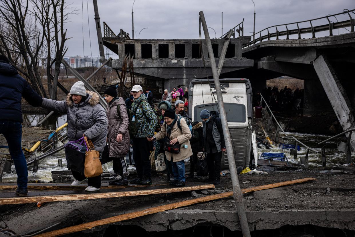 Evacuees cross a destroyed bridge as they flee the city of Irpin, northwest of Kyiv, on March 7, 2022. - Ukraine dismissed Moscow's offer to set up humanitarian corridors from several bombarded cities on March 7, 2022, after it emerged some routes would lead refugees into Russia or Belarus. The Russian proposal of safe passage from Kharkiv, Kyiv, Mariupol and Sumy had come after terrified Ukrainian civilians came under fire in previous ceasefire attempts. (Photo by Dimitar DILKOFF / AFP) (Photo by DIMITAR DILKOFF/AFP via Getty Images)