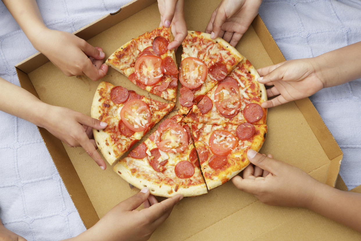 hands grabbing pizza carbs