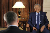 Malaysia's Prime Minister Mahathir Mohamad, right, is interviewed in Putrajaya, Malaysia, Monday, Aug. 13, 2018. Mahathir said he will seek to cancel multibillion-dollar Chinese-backed infrastructure projects that were signed by his predecessor as his government works to dig itself out of debt, and he blasted Myanmar’s treatment of its Rohingya minority as "grossly unjust." (AP Photo/Yam G-Jun)