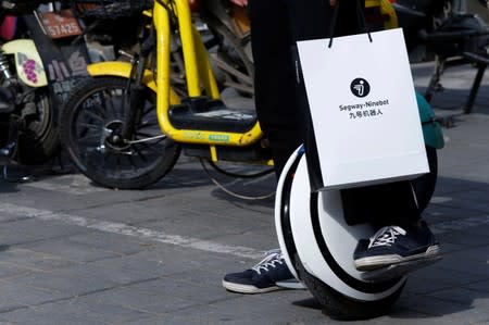 Man rides a Ninebot One electric unicycle near the venue of a Segway-Ninebot product launch event in Beijing