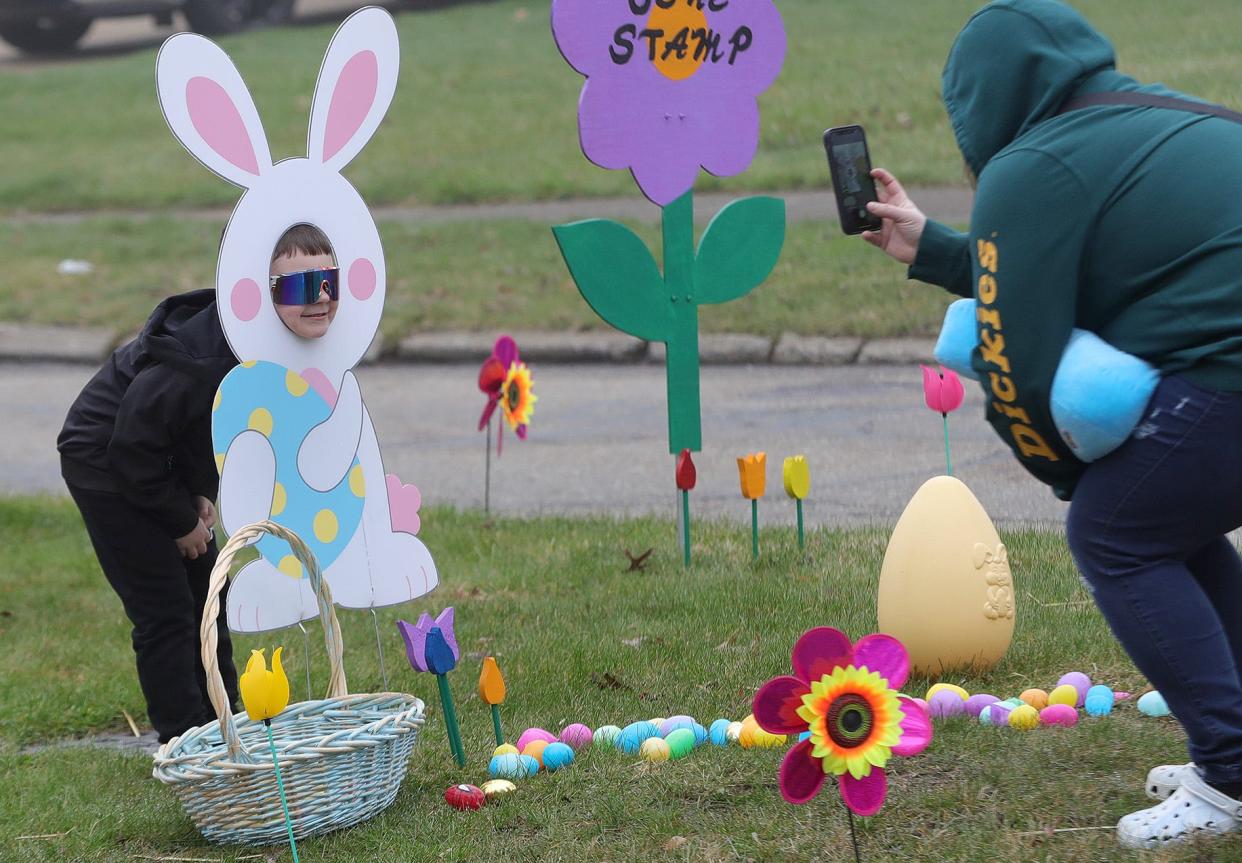 Milton Street resident Destiny Levelle, right, takes a photo of her son Rowen Wainuskis, 5, as they visit the Easter display on Sunday, March 31, 2024, on East Milton Street in Alliance.