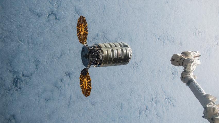     A spacecraft with two solar wings above Earth. On the right is a robotic arm. 