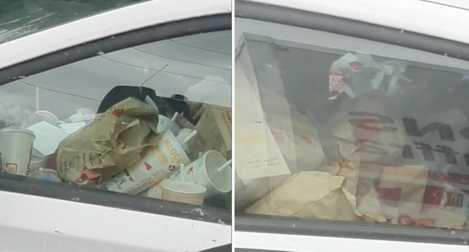 A white car in Victoria full of McDonalds rubbish while a woman is inside eating.