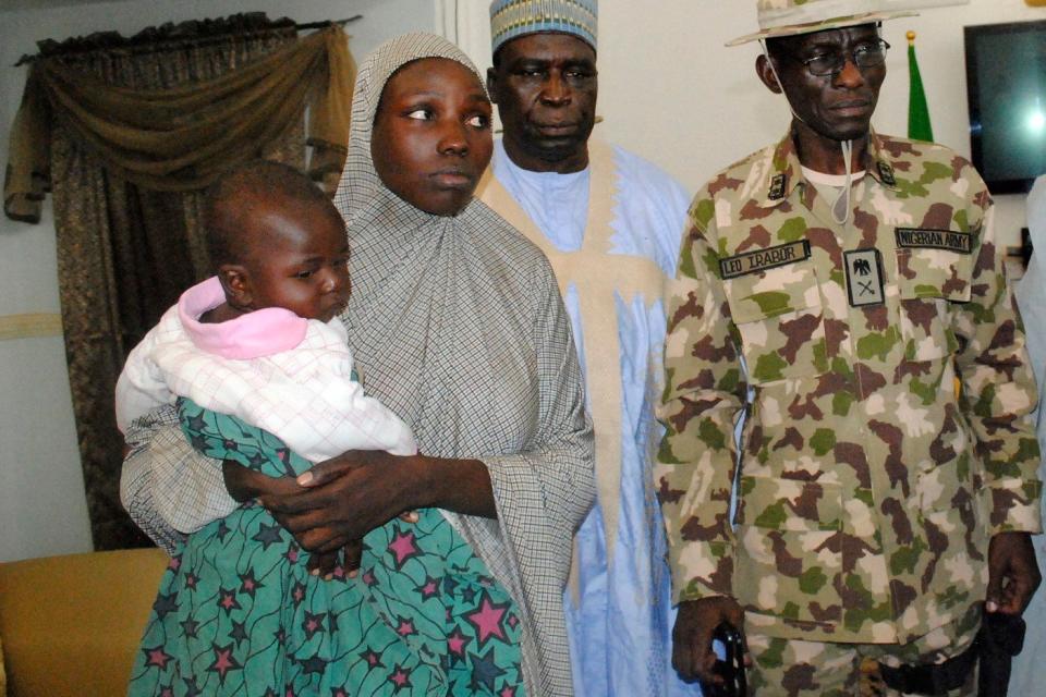 Maryam Ali Maiyanga (2-L), one of the more than 200 Chibok schoolgirls kidnapped Boko Haram Islamists in April 2014, carries her 10-month-old son while arriving at the Government House, after her rescue, on November 5, 2016 in Maiduguri