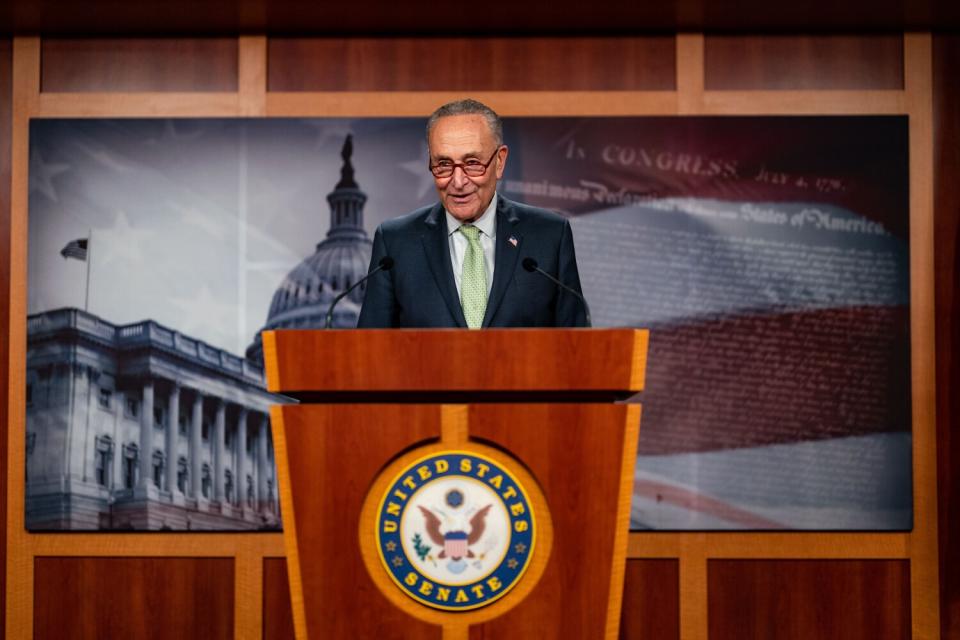 Senate Majority Leader Chuck Schumer stands at a podium.