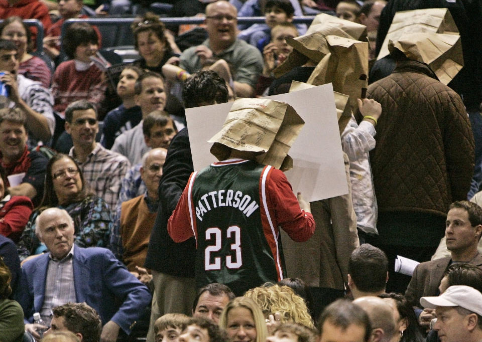 Former Milwaukee Bucks owner Herb Kohl, left, watches as fans with bags on their heads are led out of the arena in 2008. (AP)