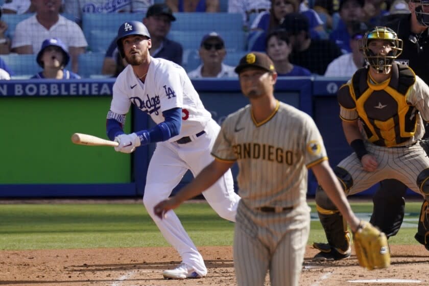 Los Angeles Dodgers' Cody Bellinger, left, runs to first as he hits a solo home run while San Diego Padres.