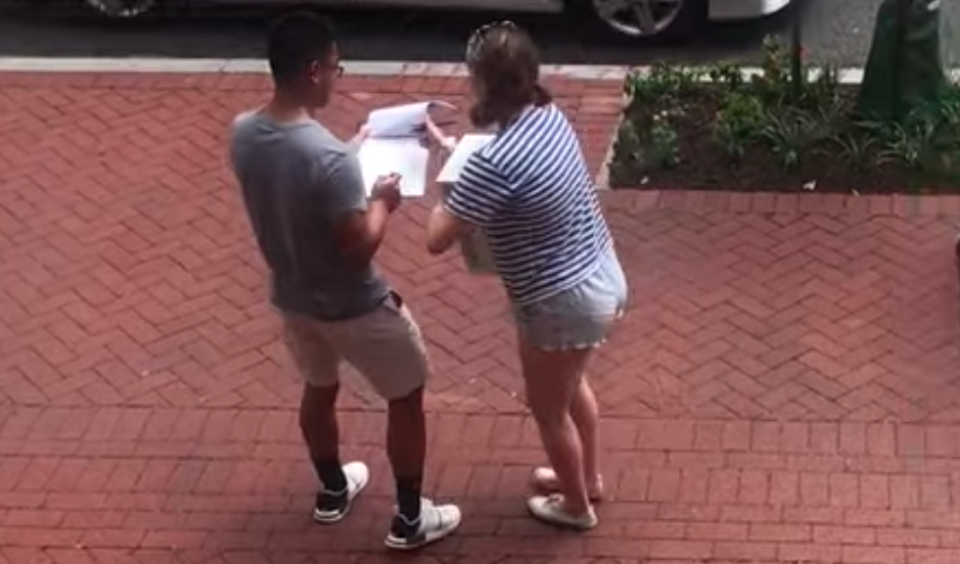 A man holds a petition while a woman leans in to sign it at George Washington University. 