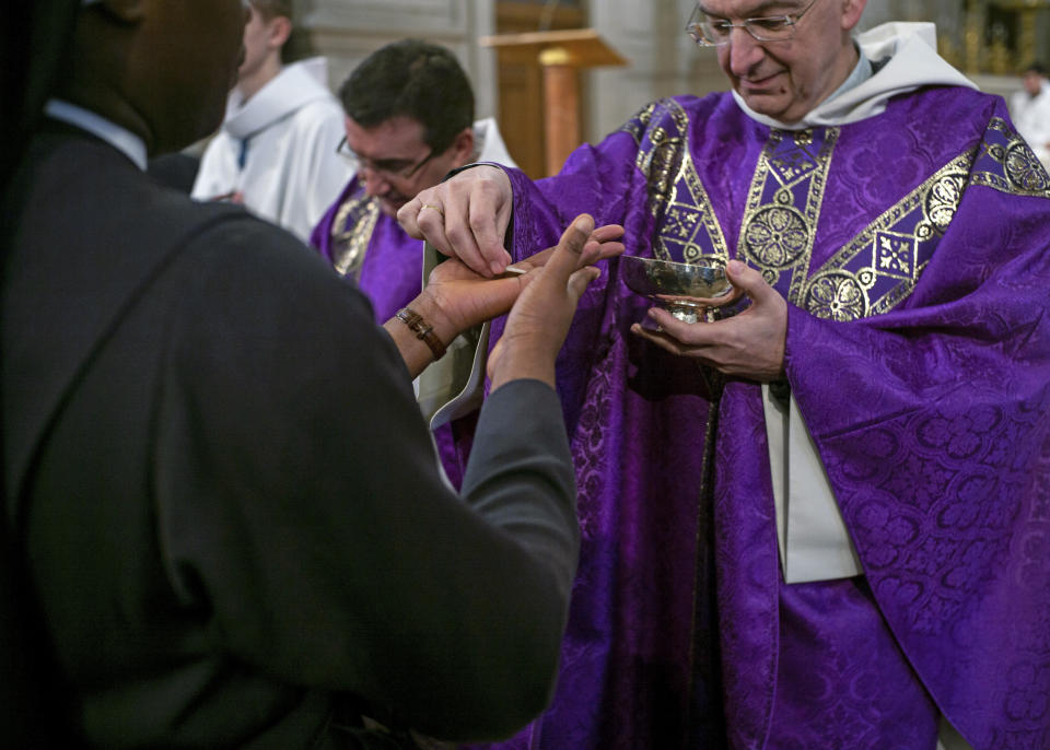 Faithful receive the holy communion into their hands during a Mass celebrated at Saint Francois Xavier church in Paris, France, Sunday, March 1, 2020. The archbishop of Paris is asking all of the French capital's parish priests to change the way they administer communion to counter the spread of the coronavirus. It said a Paris priest tested positive for the virus on Friday after returning from Italy. (AP Photo/Rafael Yaghobzadeh)