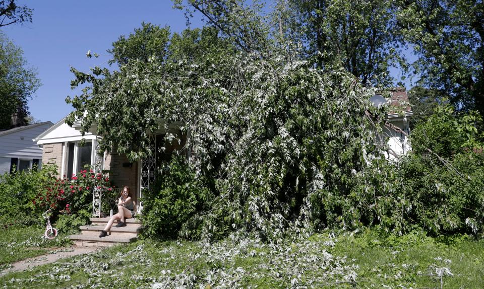 Katelyn Kostreva's 15-year-old daughter, Echo, sits on the front porch of the family's home where a tree crashed through the roof during severe storms Wednesday evening in Green Bay, Wis.