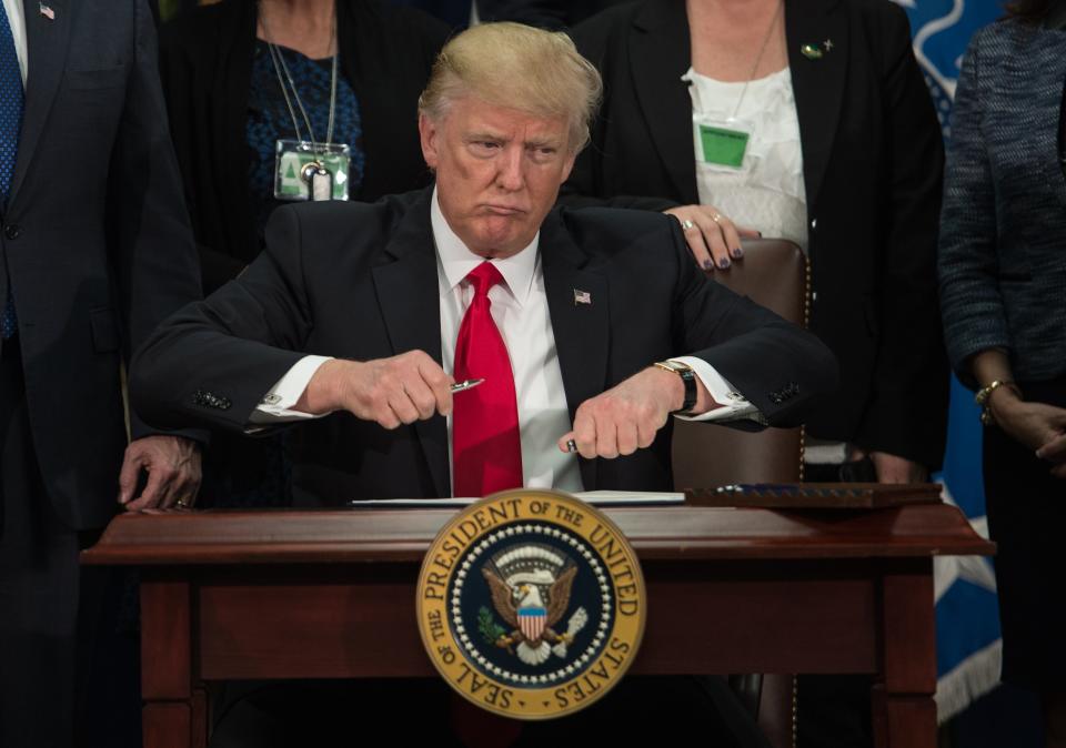 President Donald Trump takes the cap off a pen to sign an executive order to start the Mexico border wall project at the Department of Homeland Security facility in Washington, DC, on January 25, 2017.&nbsp;