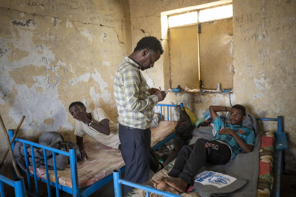 Surgeon and doctor-turned-refugee, Tewodros Tefera, checks the wounds of Hiwet Aregawi, 24, a Tigrayan who allegedly was attacked by the 'Fano' militia, young Amhara militias, in Hamdeyat Transition Center near the Sudan-Ethiopia border, eastern Sudan, Tuesday, Dec. 15, 2020. For Tewodros, the conflict has been one civilian casualty after another since shelling began in early November as he worked at a hospital in Humera. Some shelling came from the north, he said, the direction of nearby Eritrea. (AP Photo/Nariman El-Mofty)