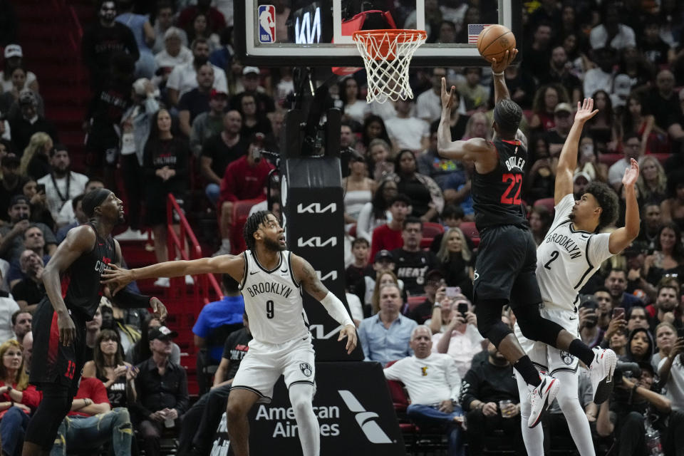 Miami Heat forward Jimmy Butler (22) jumps to score as Brooklyn Nets forward Cameron Johnson (2) defends while Nets forward Trendon Watford (9) and Miami Heat center Bam Adebayo (13) watch during the second half of an NBA basketball game, Thursday, Nov. 16, 2023, in Miami. (AP Photo/Rebecca Blackwell)