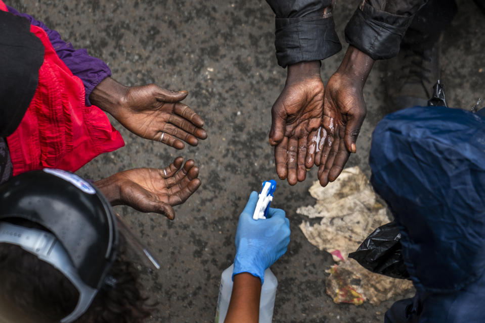 Homeless people waiting to receive food baskets from private donors, get their hands sanitized April 13, 2020, in Johannesburg. Because of South Africa's imposed lockdown to contain the spread of COVID-19, many are not able to work. (AP Photo/Jerome Delay)