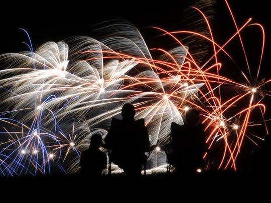 Spectators watch as the sky is lit in red, white and blue during the Independence Day fireworks show at Rodger Young Park in Fremont.