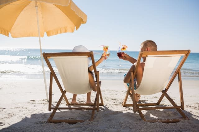 Happy couple drinking cocktails while relaxing on their deck chairs