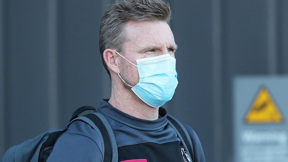 Collingwood coach Nathan Buckley is pictured wearing a face mask.