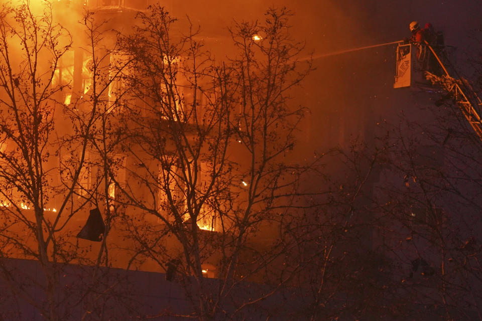 Firefighters spray water on a housing block as it burns in Valencia, Spain, Thursday, Feb. 22, 2024. The cause of the fire is unknown and if there are any victims. (AP Photo/Alberto Saiz)