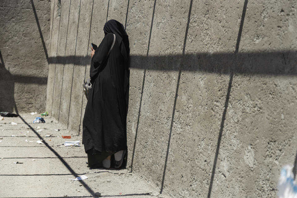 A woman of families of suspected Islamic State group fighters, checks her phone as she waits to be transferred by U.S.-backed Syrian Democratic Forces (SDF) fighters from al-Hol camp, in Hasakeh province, Syria, Wednesday, May 8, 2024. Scores of Syrian women and children linked to the Islamic State group left a sprawling camp in northeast Syria Wednesday and headed home to the eastern province of Deir el-Zour following mediation by tribal leaders. (AP Photo/Baderkhan Ahmad)