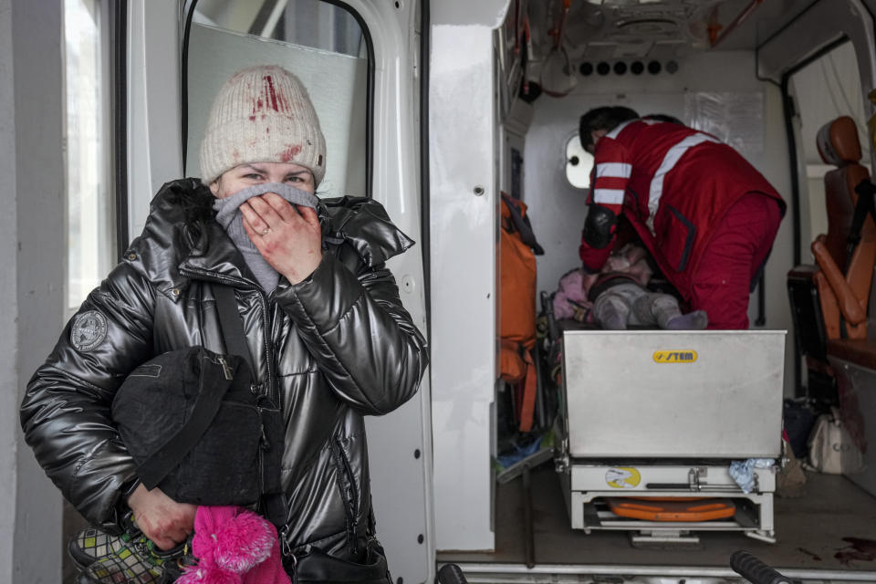 A woman reacts as paramedics perform CPR on a girl.